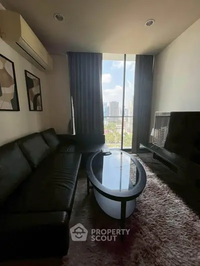 Modern living room with city view, featuring sleek black furniture and large window.