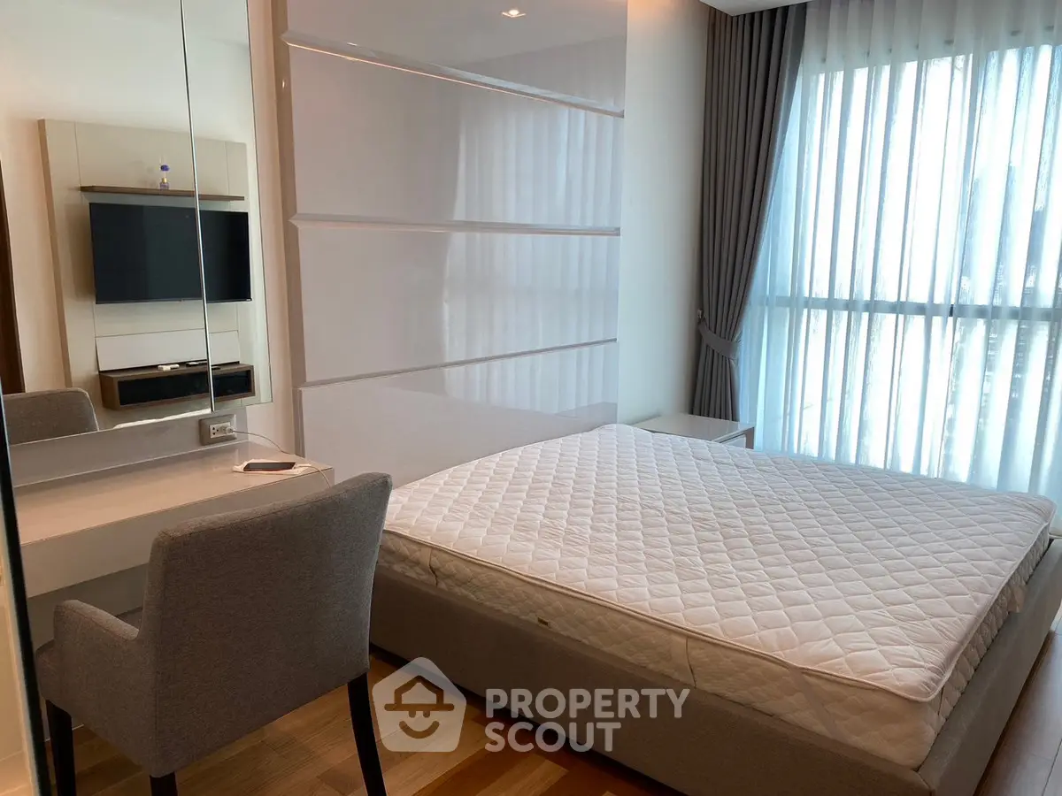 Modern bedroom with large window and stylish furniture in a bright apartment.