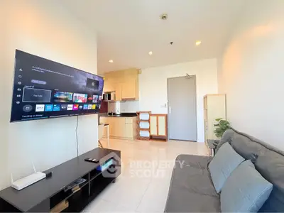 Modern living room with wall-mounted TV and cozy seating in a bright apartment