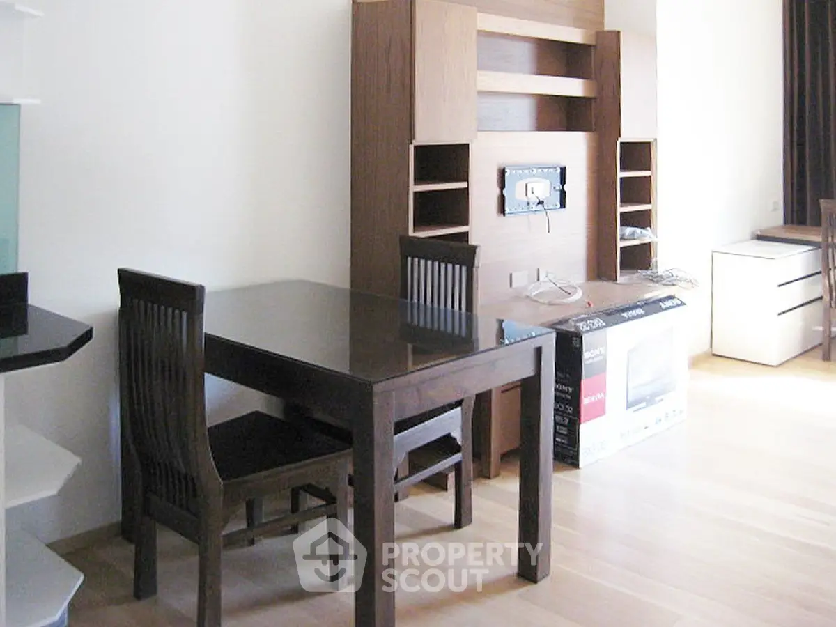 Modern dining area with wooden table and chairs, sleek entertainment unit, and natural light.