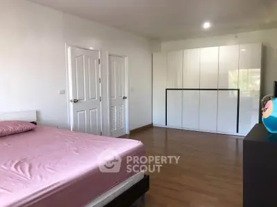 Spacious bedroom with modern wardrobe and wooden flooring