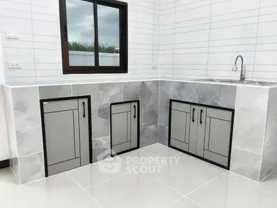 Modern kitchen with sleek cabinetry and tiled backsplash, featuring a large window for natural light.
