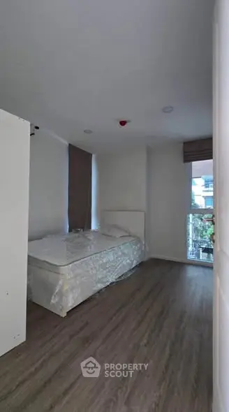 Cozy bedroom with modern flooring and large window for natural light.