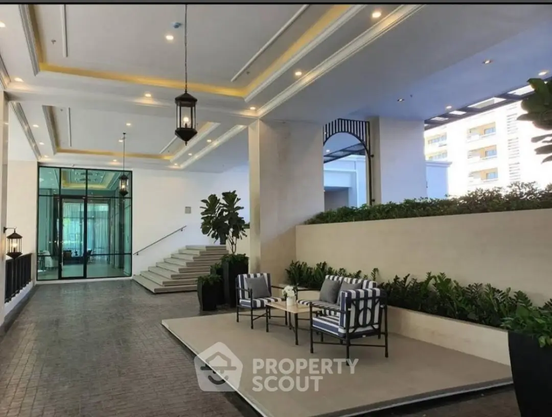 Luxurious building entrance with elegant seating and lush greenery, perfect for a sophisticated lifestyle.