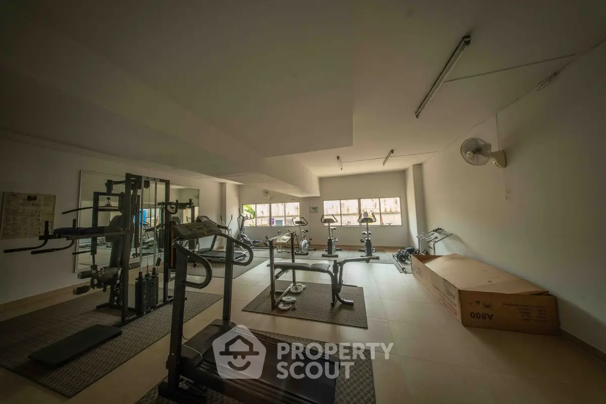 Spacious gym with modern equipment and ample natural light, perfect for fitness enthusiasts.