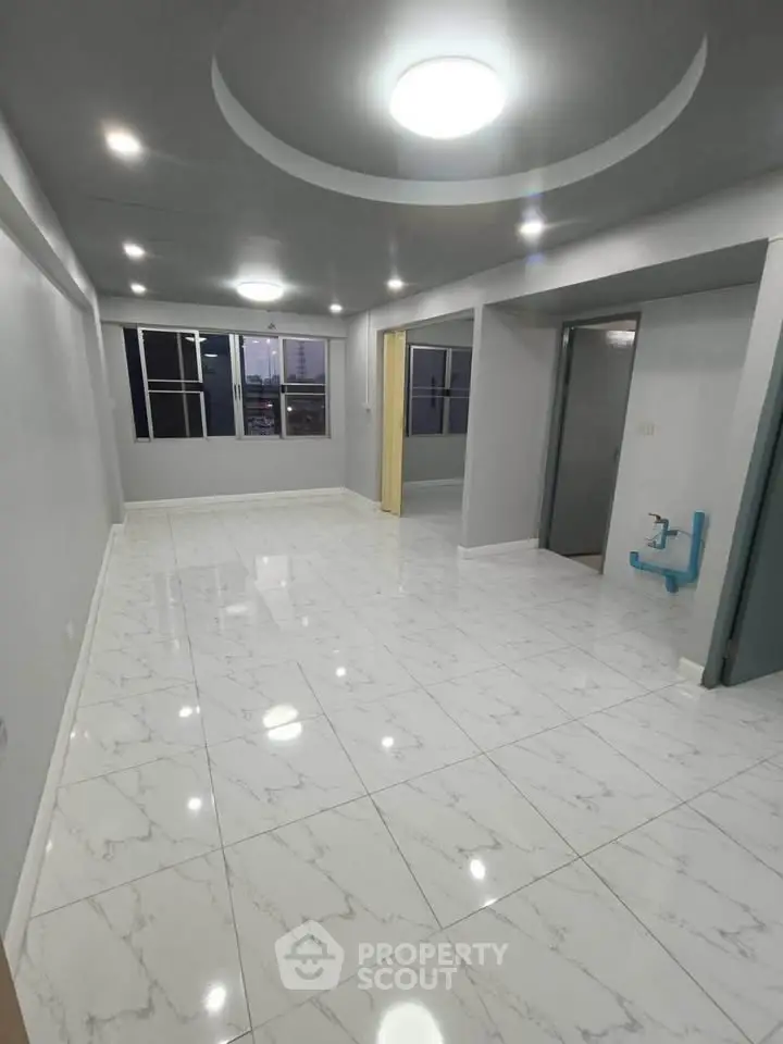 Spacious modern living room with elegant white marble flooring and recessed lighting.