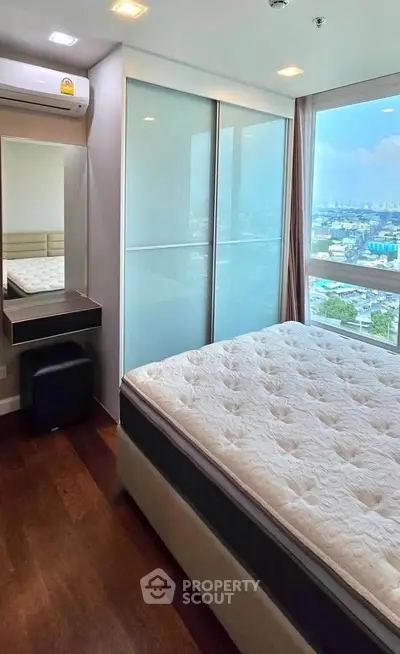 Modern bedroom with large window offering stunning city view, featuring sleek furniture and ample natural light.