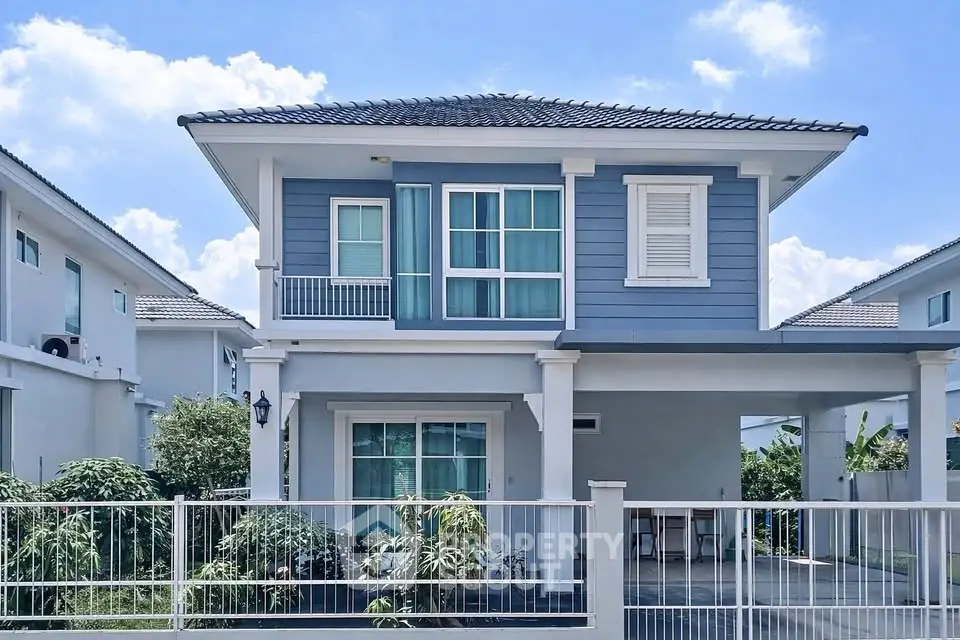 Charming two-story blue house with modern design and spacious front yard in a serene neighborhood.