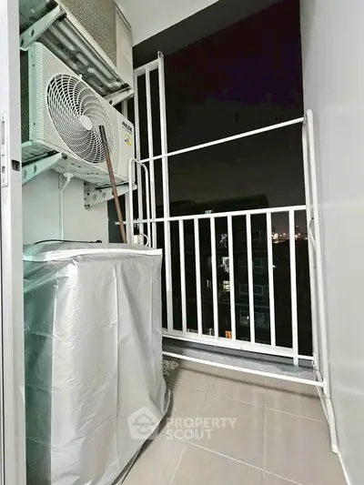 Compact balcony with air conditioning unit and city night view.