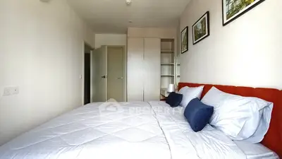 Spacious bedroom with modern decor and ample natural light, featuring a comfortable bed and stylish storage solutions.