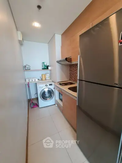 Modern compact kitchen with stainless steel appliances and washing machine