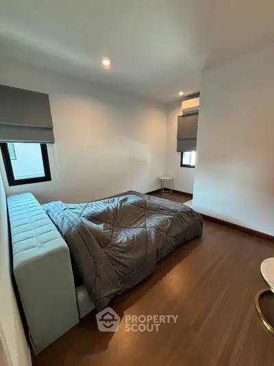 Cozy modern bedroom with wooden flooring and stylish gray bedding