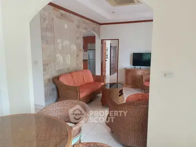 Charming living room with wicker furniture and TV, featuring stone accent wall and cozy ambiance.