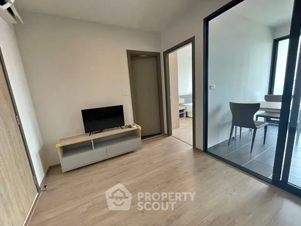 Modern living room with sleek furniture and adjacent dining area, featuring large windows for natural light.