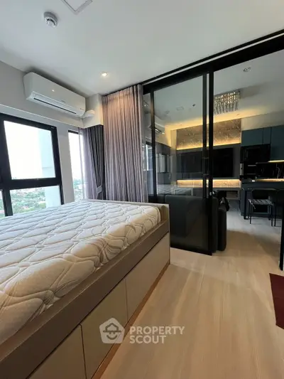 Modern bedroom with sliding glass doors leading to a stylish living area, featuring sleek furniture and ambient lighting.