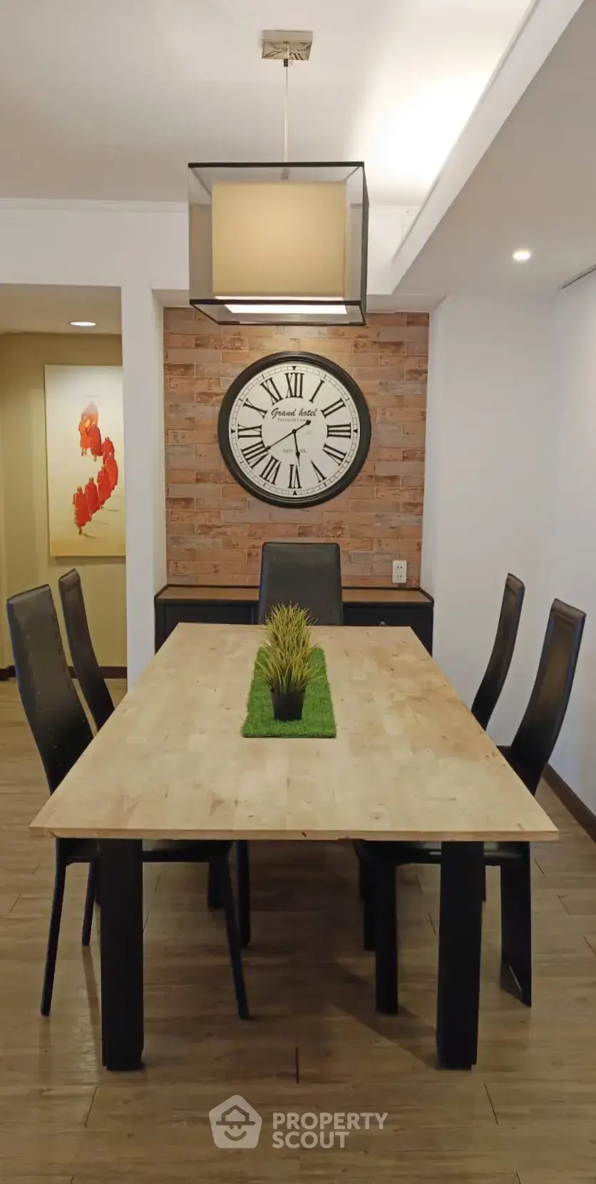 Stylish dining room with modern decor and elegant clock on brick accent wall.