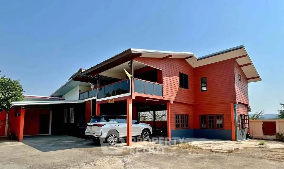 Spacious two-story red house with carport and modern design in a serene neighborhood.