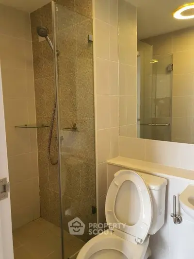 Modern bathroom with glass shower and sleek fixtures in contemporary apartment.