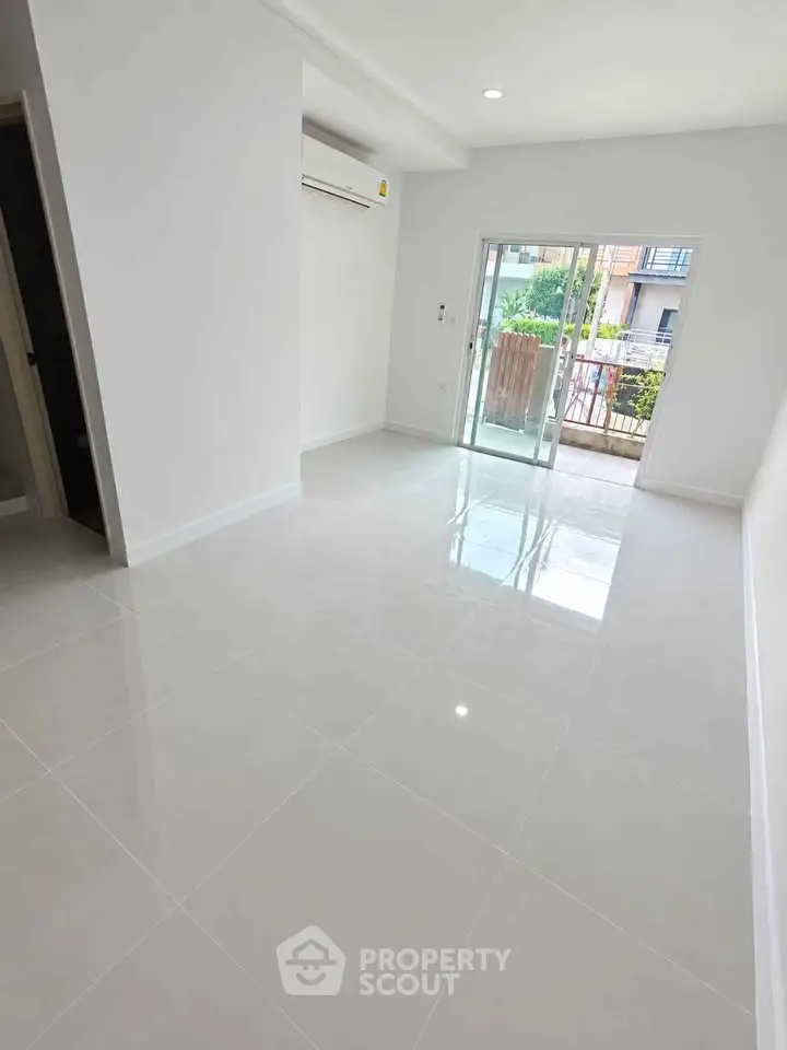 Spacious modern living room with glossy tile flooring and balcony access.