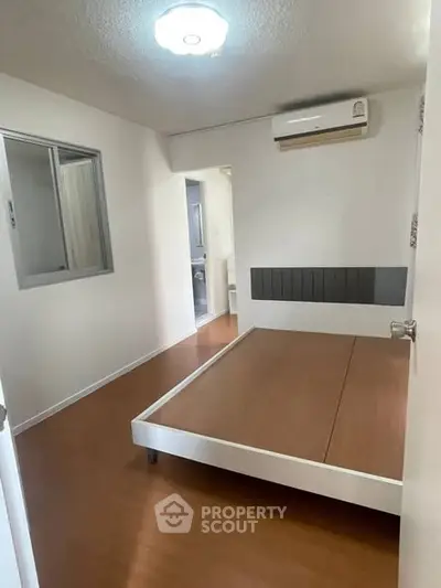 Spacious bedroom with modern bed frame and air conditioning in a minimalist design.