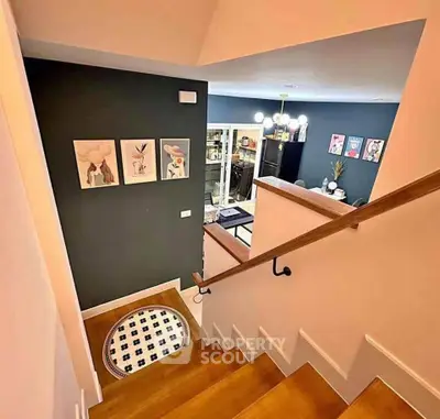 Stylish staircase leading to a modern living room with chic decor and artwork.