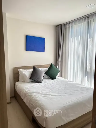 Cozy bedroom with modern decor and natural light from large window.