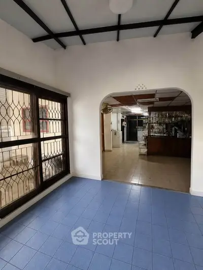 Spacious interior with tiled flooring and large windows, ideal for versatile living space.