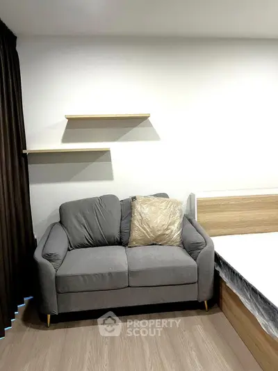 Modern living room with stylish gray sofa and wooden shelves, perfect for cozy relaxation.