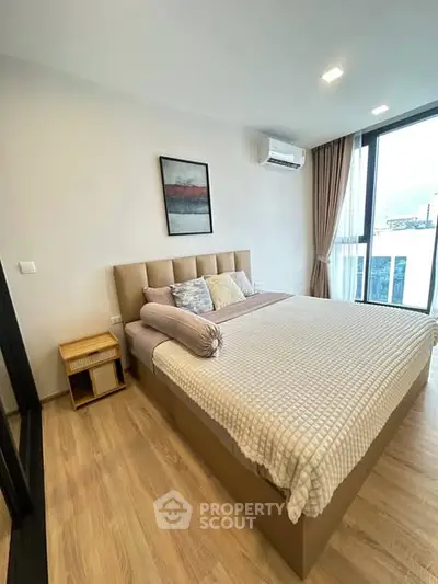 Modern bedroom with large window and stylish decor in a high-rise apartment.