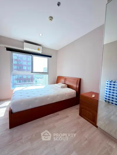 Bright and airy bedroom with large window and modern furnishings in a high-rise apartment.