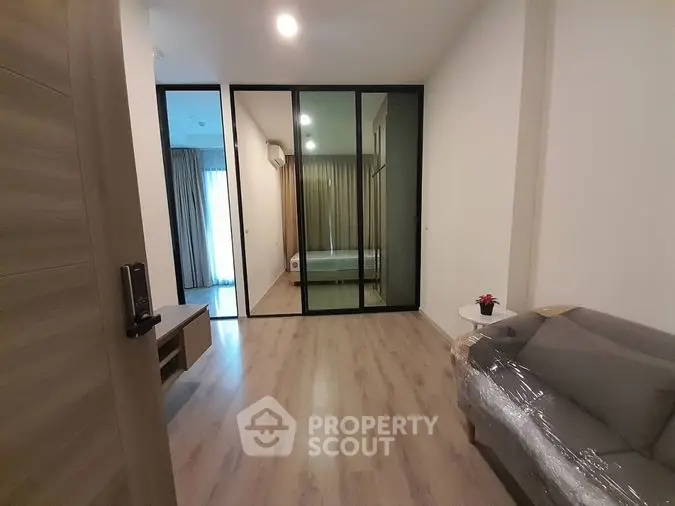 Modern living room with sleek wooden flooring, large glass balcony doors, and contemporary furnishings, perfect for urban living.