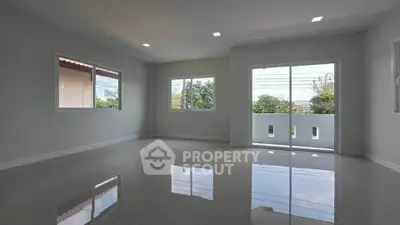 Spacious and bright living room with large windows and glossy tiled floors.