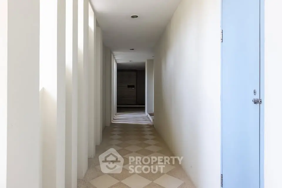 Bright corridor with checkered flooring and light blue door in modern building.