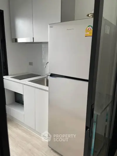 Modern compact kitchen with sleek white cabinets and stainless steel appliances