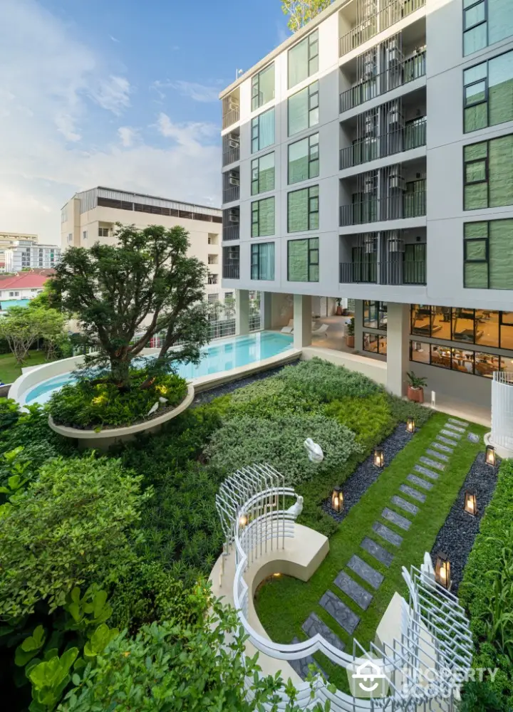 Modern apartment building with lush garden and pool view, showcasing urban luxury living.