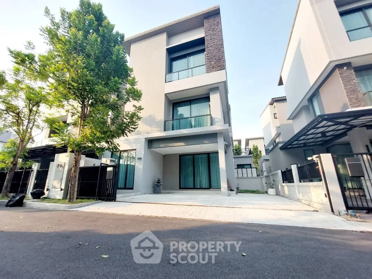 Modern three-story house with large windows and driveway in a serene neighborhood.
