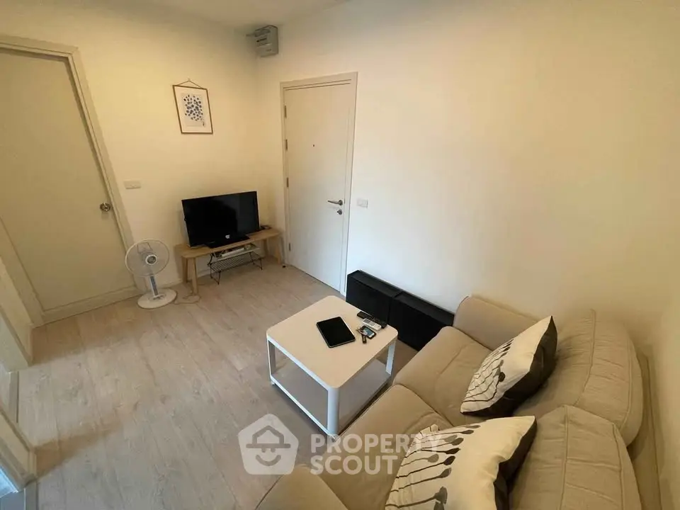 Cozy living room with modern decor and neutral tones, featuring a comfortable sofa and a flat-screen TV.