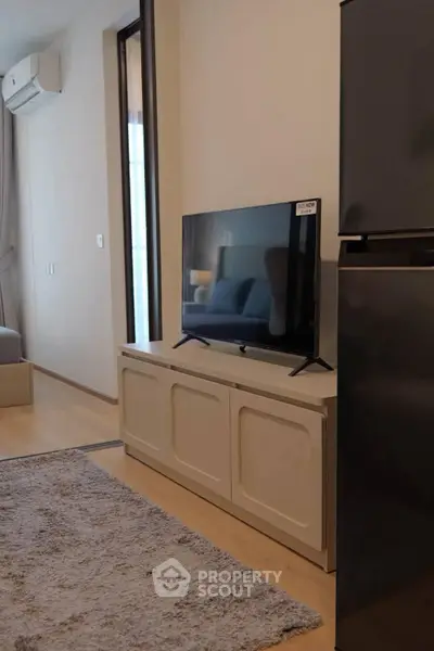 Modern living room with sleek TV setup and cozy rug, perfect for relaxation.