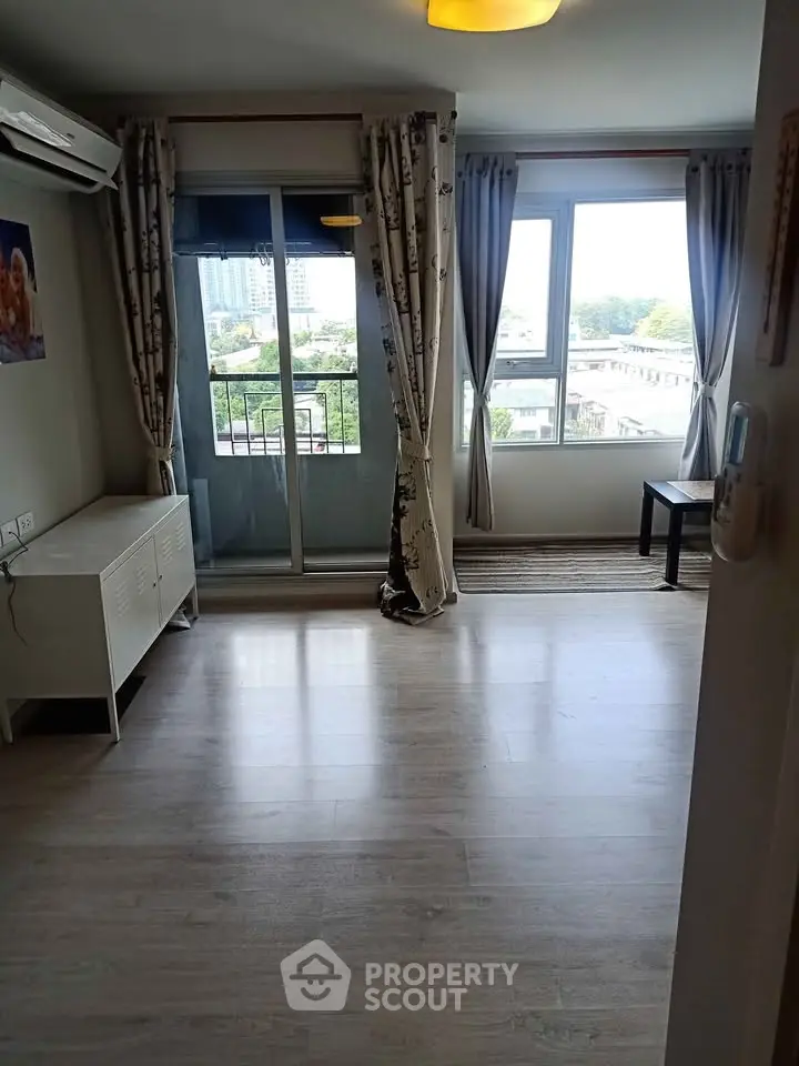 Spacious living room with balcony and city view, featuring modern flooring and natural light.