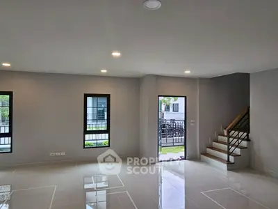 Spacious modern living room with large windows and staircase, perfect for family gatherings.