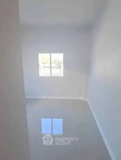 Bright empty room with glossy floor and large window offering natural light.