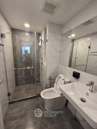 Modern bathroom with sleek design, featuring a glass shower enclosure and elegant fixtures.