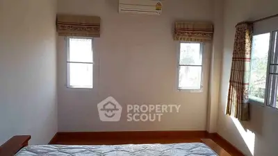 Bright bedroom with large windows and air conditioning, perfect for a cozy retreat.