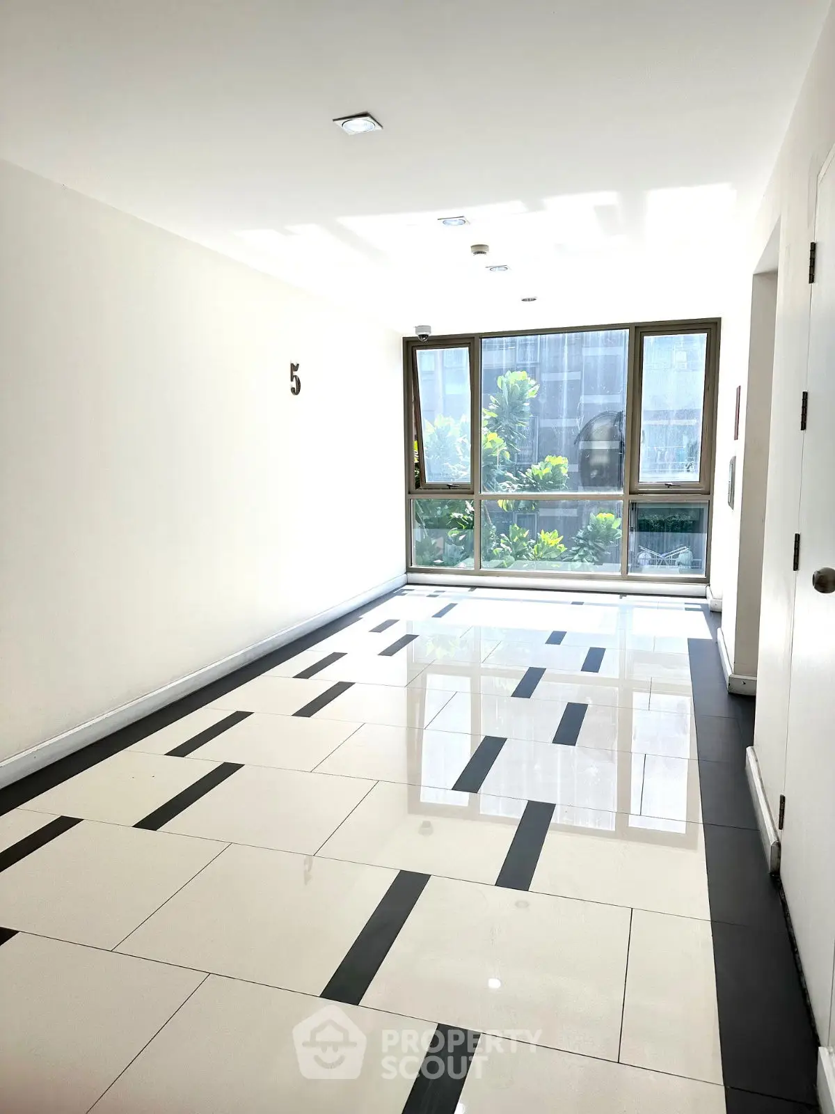 Bright and modern hallway with large windows and stylish tile flooring in a contemporary building.