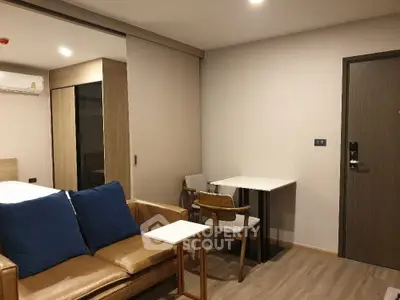 Modern studio apartment with cozy seating and dining area, featuring sleek wooden flooring.