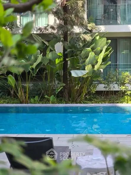 Luxurious apartment poolside view with lush greenery and modern design.