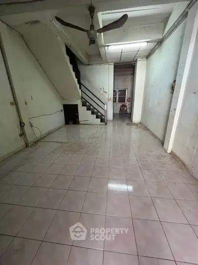 Spacious interior with tiled flooring and staircase, ideal for renovation or customization.