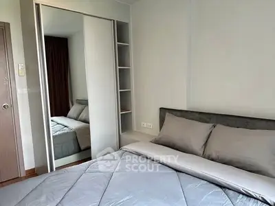 Modern bedroom with mirrored wardrobe and cozy bedding in stylish apartment.
