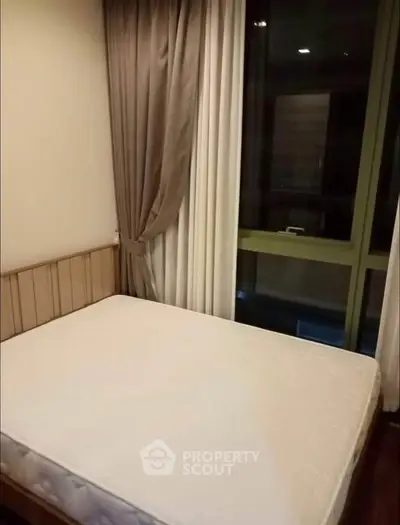 Cozy bedroom with large window and elegant curtains in modern apartment.