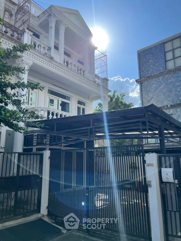 Elegant multi-story building with classical columns and gated entrance under a bright blue sky.